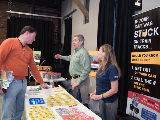 Two men and a woman talking at a community fair