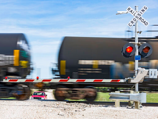 Blurred tanker cars going through a level crossing with safety gate down