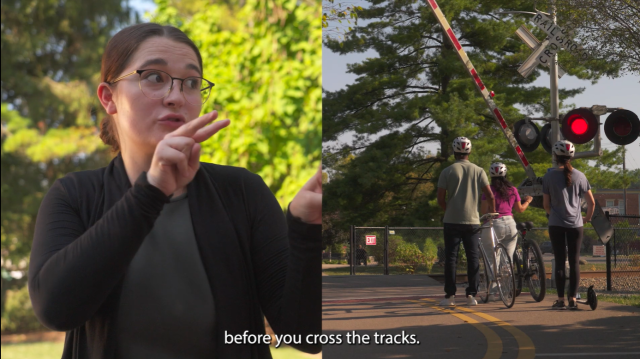 Woman signing with American Sign Language to Look next to image of a pedestrian railroad crossing