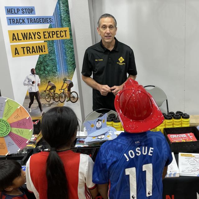 Volunteer sharing a rail safety message with event attendees.