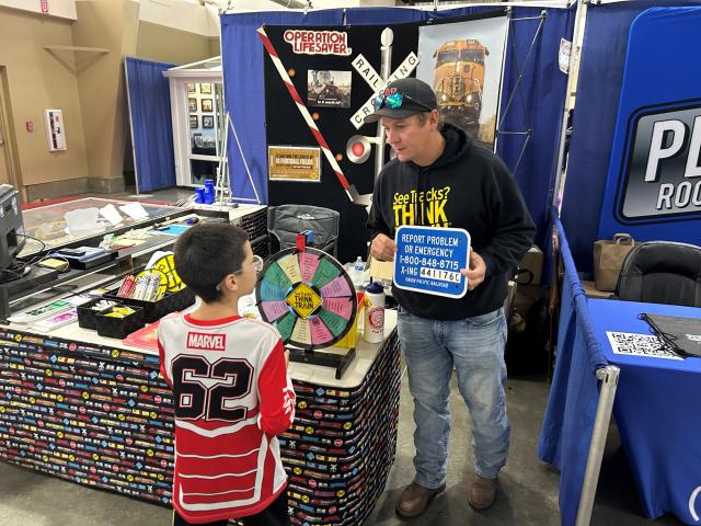A volunteer shows a young visitor an Emergency Notification System sign.