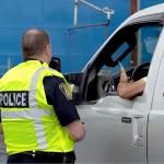 a police officer next to a car near a railroad crossing