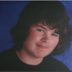 a close up of a teen boy with a black tshirt