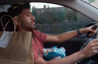 a man in a car with a food delivery bag